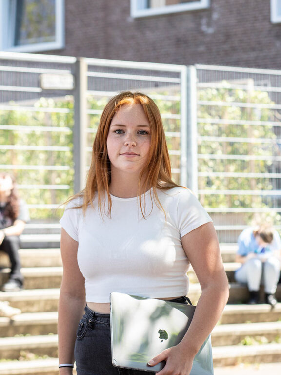 Een student Communicatie en Marketing met een laptop in haar handen