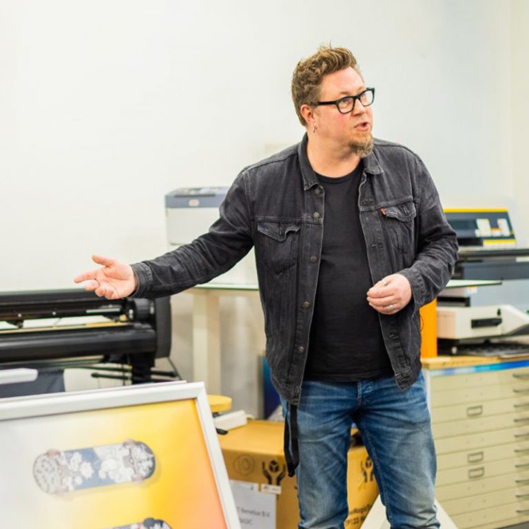 Docent Jeroen geeft uitleg over de snijmachine.