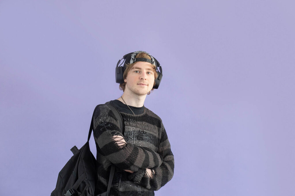 Een jongen met zijn armen over elkaar geslagen en een koptelefoon op zijn hoofd