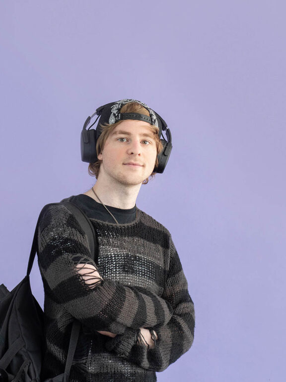 Een jongen met zijn armen over elkaar geslagen en een koptelefoon op zijn hoofd
