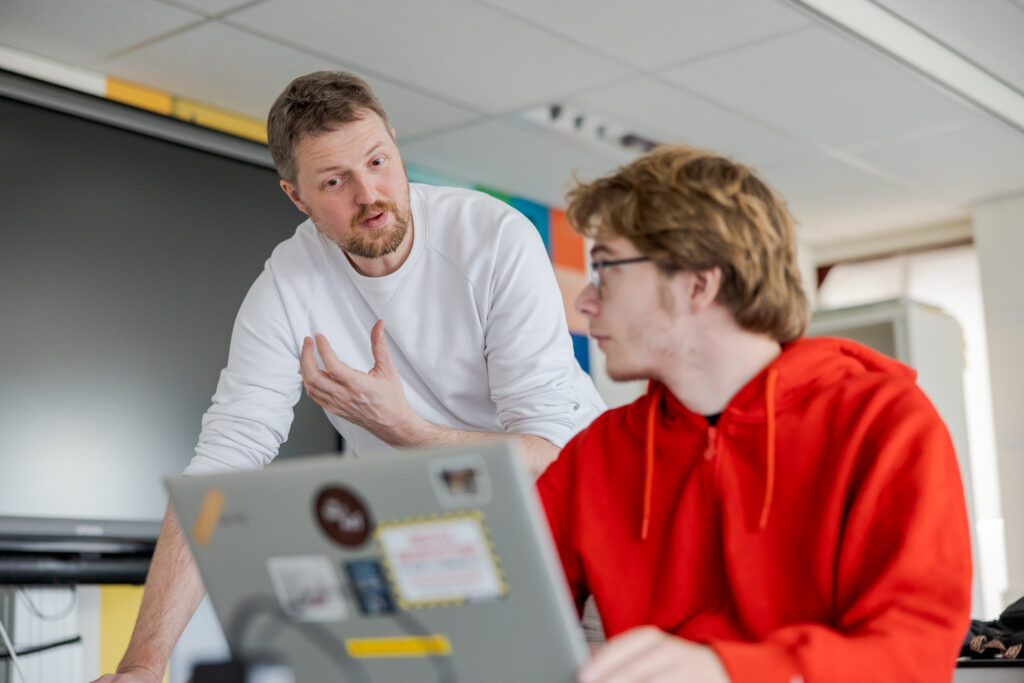 Docent geeft student uitleg over de opdracht.