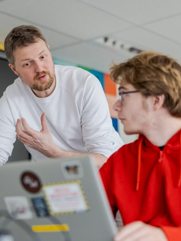 Docent geeft student uitleg over de opdracht.