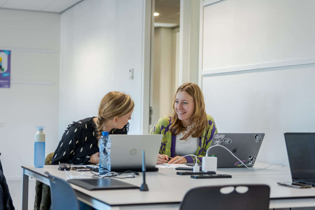 Twee studenten Crossmedia aan het werk op de computer.