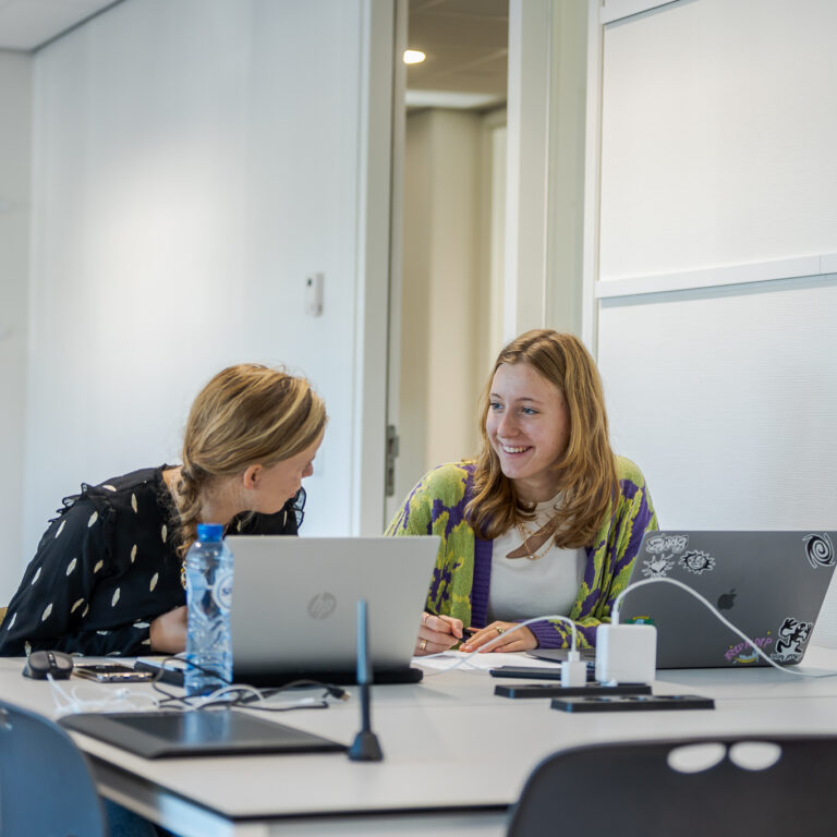 Twee studenten Crossmedia aan het werk op de computer.