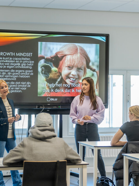 Studenten presenteren voor een grote groep.