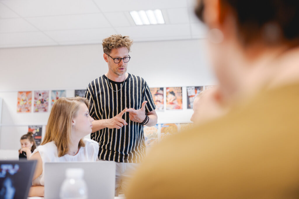 Docent geeft uitleg aan twee studenten.