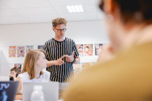 Docent geeft uitleg aan twee studenten.
