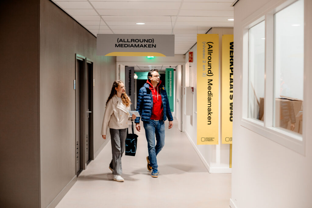 Studiekiezer en ouder zijn door de school aan het lopen tijdens de Open Dag