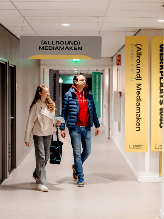 Studiekiezer en ouder zijn door de school aan het lopen tijdens de Open Dag