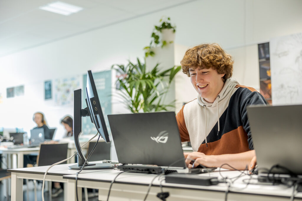 Een student bouwt op zijn laptop een game