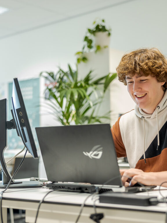Een student bouwt op zijn laptop een game