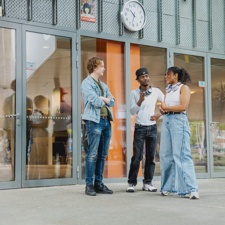 Studenten staan in het atrium te overleggen over de opdracht van de klant