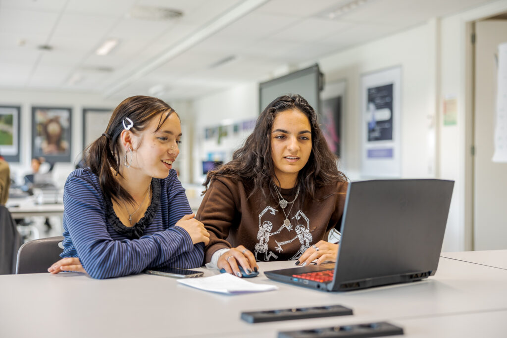 Twee studenten werken samen aan een programmeer opdracht.