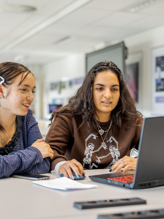 Twee studenten werken samen aan een programmeer opdracht.