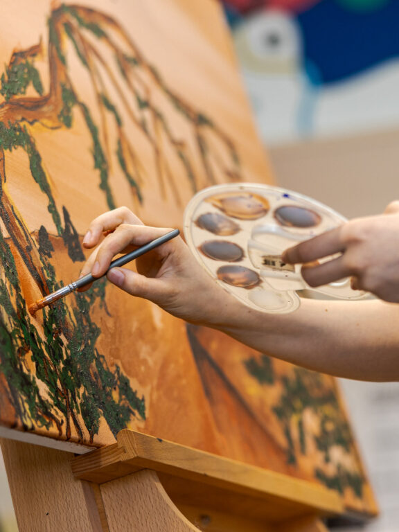 Student Creative Media Design is aan het schilderen in de creatieve werkplaats.