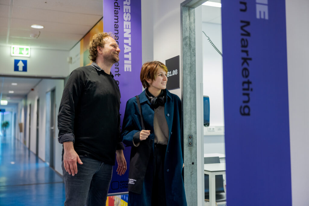 Een ouder en student kijken in een lokaal tijdens de open dag