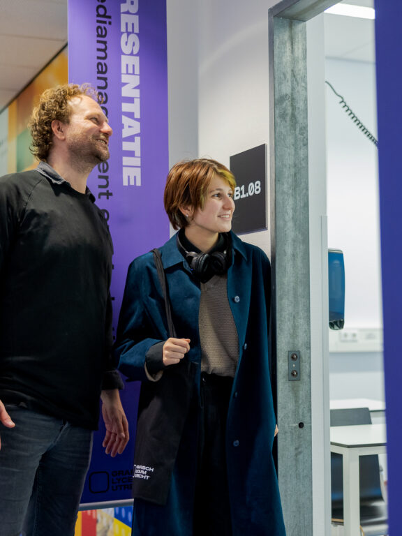 Een ouder en student kijken in een lokaal tijdens de open dag