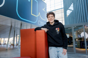Student is aan het relaxen bij de rode bank in het atrium