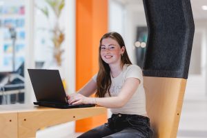 Student achter haar laptop met een brede glimlach